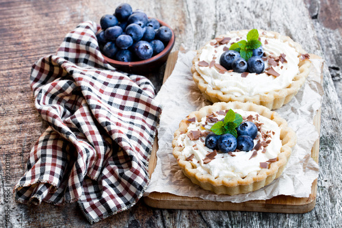 Delicious  tarts with cream and fresh blueberry on wooden table