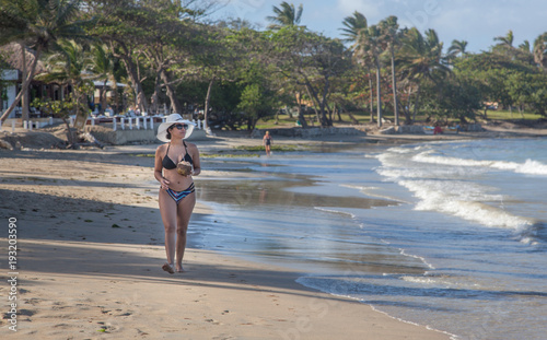 Latina woman on holiday drinking a coconut on the beach 3