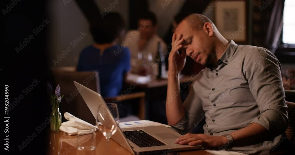 4K Concerned businessman on working lunch, working on laptop & looking at business figures