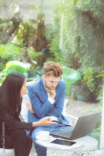 technology and office concept - two business man and woman with laptop - tablet pc computer and papers having discussion in office.