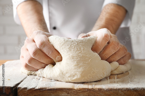 Man kneading dough on wooden board sprinkled with flour photo