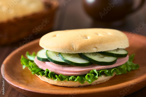Sandwich aus Chilenischem Hallulla Brötchen belegt mit Salatblatt, Aufschnitt und Gurke, fotografiert mit natürlichem Licht (Selektiver Fokus, Fokus auf die Vorderseite des Sandwichs) photo