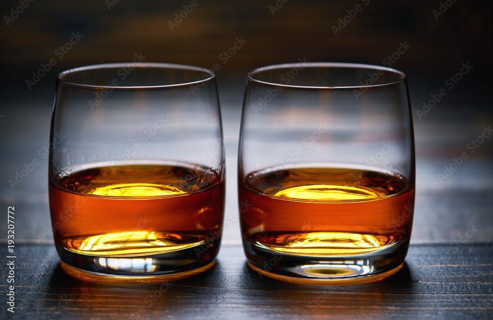 Two glasses of old whiskey on wooden table
