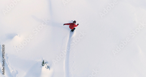 Snowboarding Overhead Top Down View of Snowboarder Riding Through Fresh Powder Snow Down Ski Resort or Backcountry Slope - WInter Extreme Sports Background