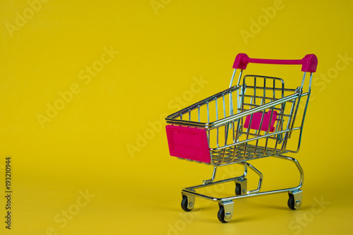 Shopping cart or supermarket trolley on yellow background, business finance shopping concept.