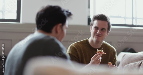 Young male friends eating pizza at home photo