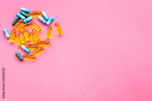 Color capsules. Medicine pills on pink background top view copy space