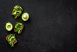 Snacks with avocado. Avocado toast with rye bread on black background top view copy space