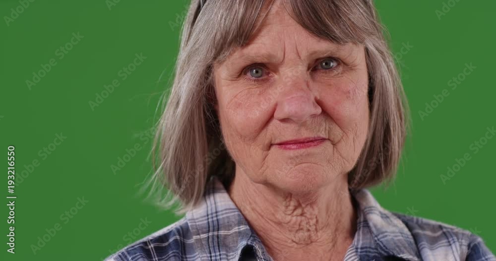 Close view of somber elderly woman isolated on green screen