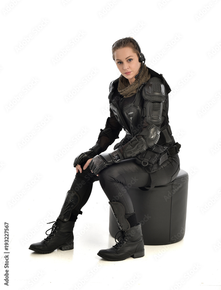 full length portrait of female wearing black  tactical armour, crouching pose, isolated on white studio background.