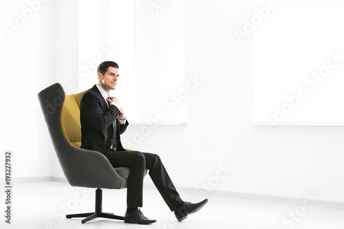 Handsome businessman sitting in comfortable armchair indoors