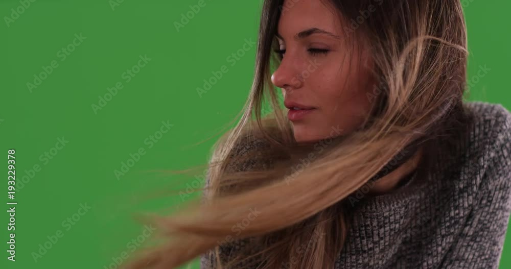 Close up of beautiful millennial woman with long brunette hair blowing in the wind on greenscreen. Thoughtful and serious young lady looking to the side. 4k on green for keying or compositing
