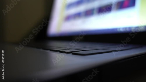 Hands working on laptop. Dark office environment.