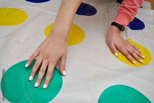 A Girl Plays Twist Game on the Floor, Hand on Colorful Circles. Trends in children's anti-stress toys for attention photo