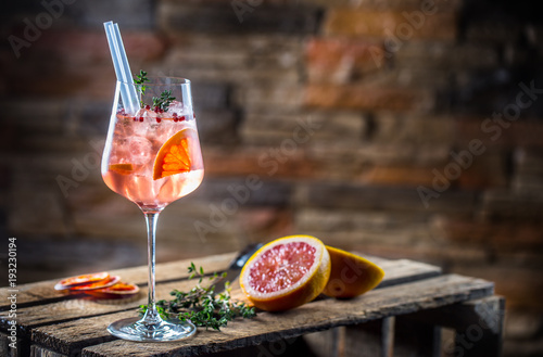 Cocktail drink on a old  wooden board. Alcoholic beverage with tropical fruits red pepper herb and ice