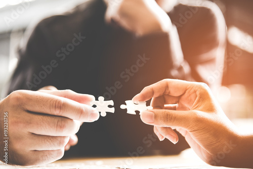 .Businessman team work holding two jigsaw connecting couple puzzle piece for matching to goals target, success and start up new project in office.  Business Concept. photo