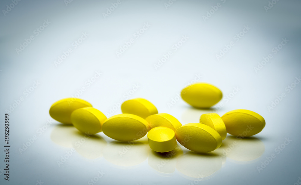 Yellow oval tablet pills with shadows on white background with beautiful creative pattern and copy space for text. Mild to moderate pain management. Pain killer medicine. Yellow oval tablet pills with shadows on white background with beautiful creative pattern and copy space for text. Mild to moderate pain management. Pain killer medicine.