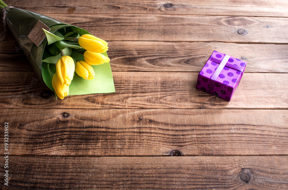 yellow tulips and gift on a wooden background yellow tulips and gift on a wooden background