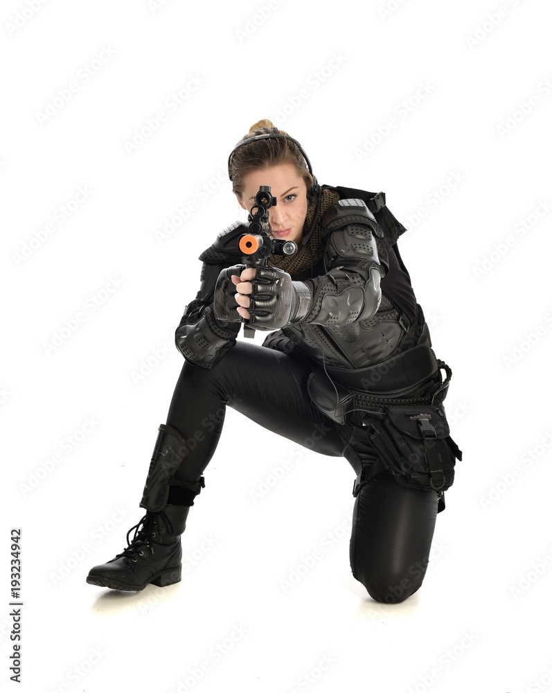 full length portrait of female wearing black tactical armour, crouching pose holding a weapon, isolated on white studio background. full length portrait of female wearing black tactical armour, crouching pose holding a weapon, isolated on white studio background.