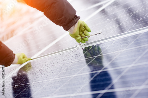 Male installs solar batteries using tools in snow-covered weather by dressing uniforms and gloves. Macro photography. photo