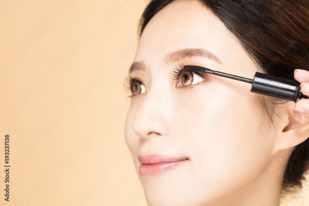 Young Woman With Makeup Brush Applying Black Mascara On Eyelashes. Young Woman With Makeup Brush Applying Black Mascara On Eyelashes.