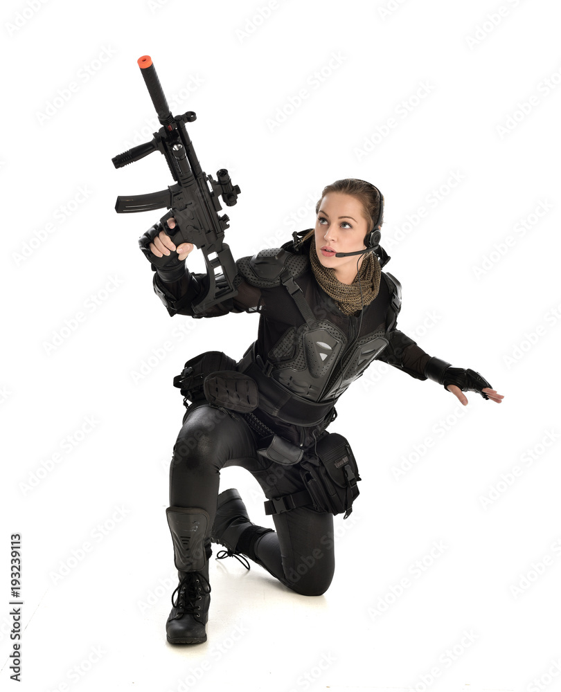 full length portrait of female wearing black tactical armour, crouching pose holding a weapon, isolated on white studio background. full length portrait of female wearing black tactical armour, crouching pose holding a weapon, isolated on white studio background.
