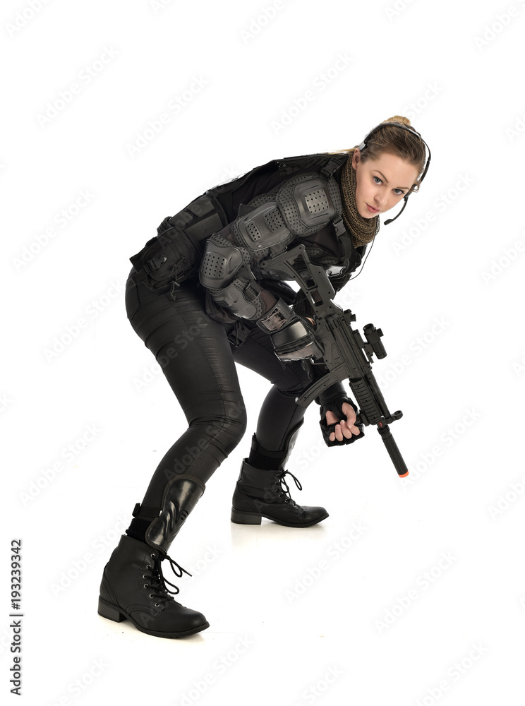 full length portrait of female wearing black tactical armour, crouching pose holding a weapon, isolated on white studio background. full length portrait of female wearing black tactical armour, crouching pose holding a weapon, isolated on white studio background.