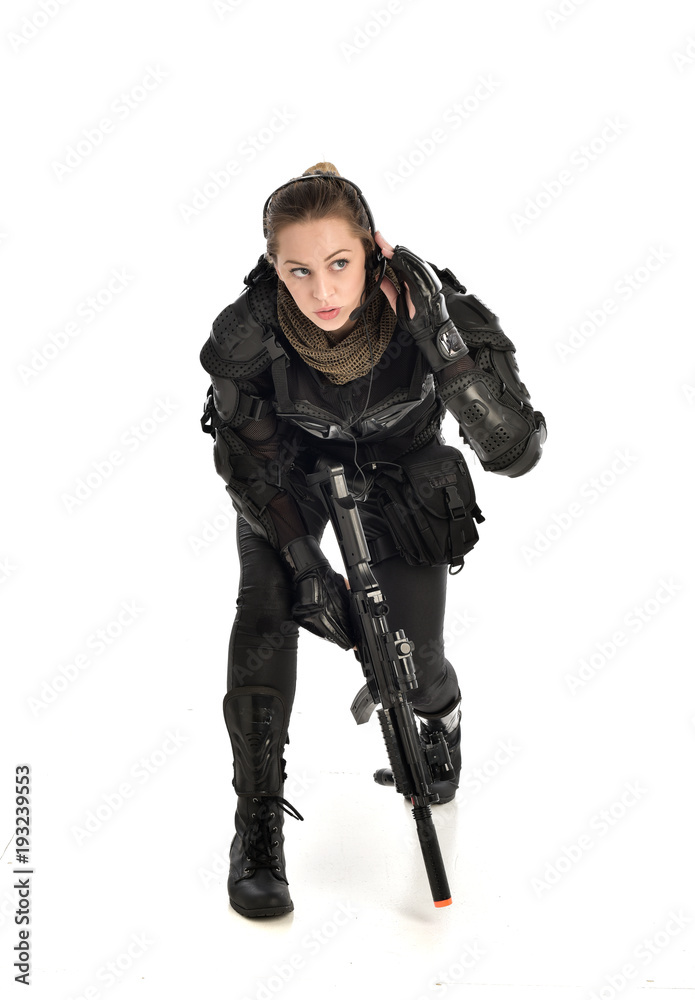full length portrait of female wearing black tactical armour, crouching pose holding a weapon, isolated on white studio background. full length portrait of female wearing black tactical armour, crouching pose holding a weapon, isolated on white studio background.