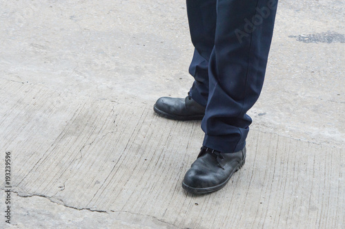 Leg of man with long black trousers standing on the street., business men shoes stand on walking street