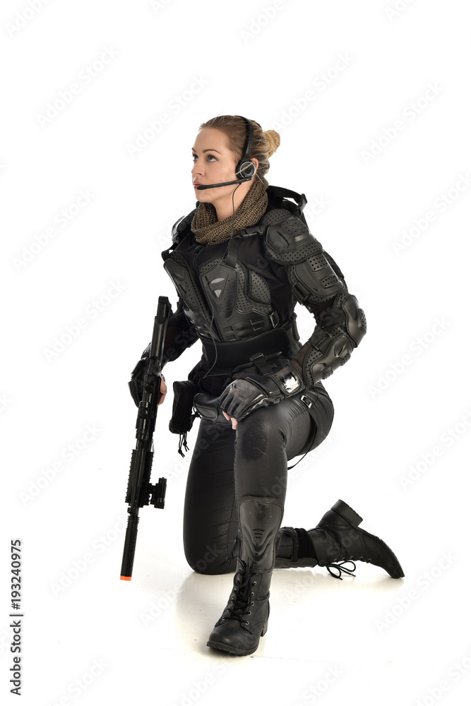 full length portrait of female wearing black tactical armour, crouching pose holding a weapon, isolated on white studio background. full length portrait of female wearing black tactical armour, crouching pose holding a weapon, isolated on white studio background.