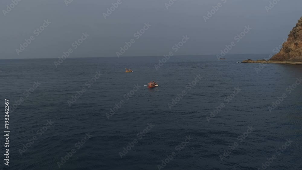 Aerial shot of people kayaking in the sea during summer day. Travel tropical island holiday concept Aerial shot of people kayaking in the sea during summer day. Travel tropical island holiday concept