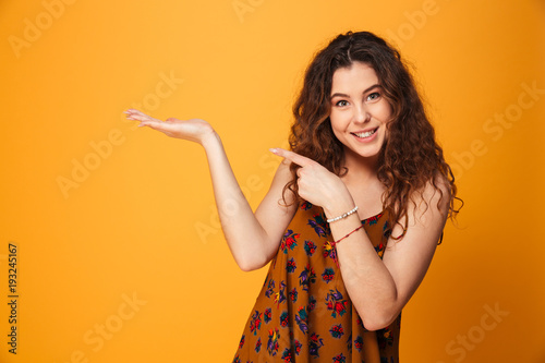 Portrait of a smiling curly haired girl pointing finger away