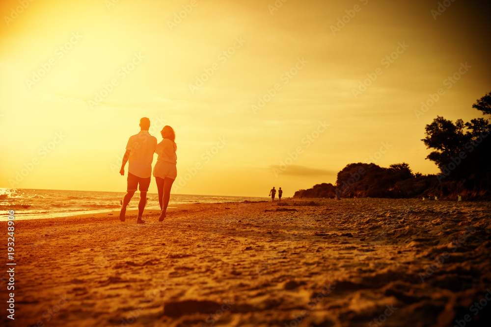 Fototapeta premium Summer golden sunset and two lovers on beach