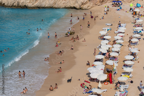 People enjoying sun and sea at the turquoise sea and sandy beach of Kaputas, Kas, Antalya, Turkey.