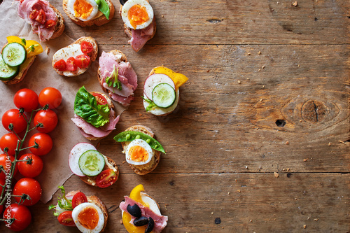 Top view of variety of healthy sandwiches on wooden table with space for text.