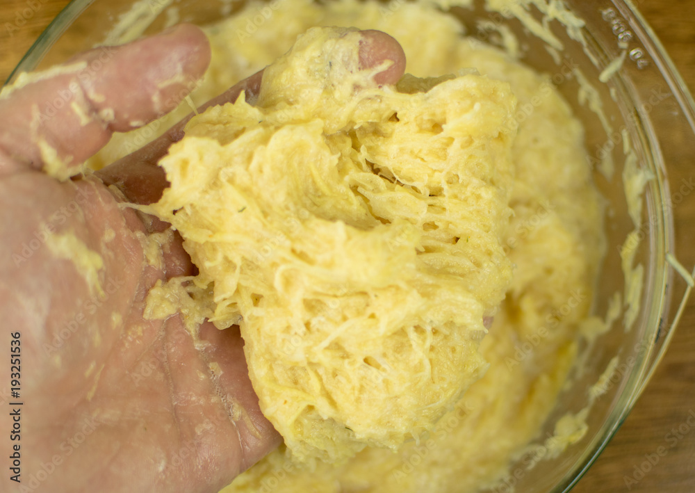 The hand is kneading grated potatoes to make dough. The hand is kneading grated potatoes to make dough.