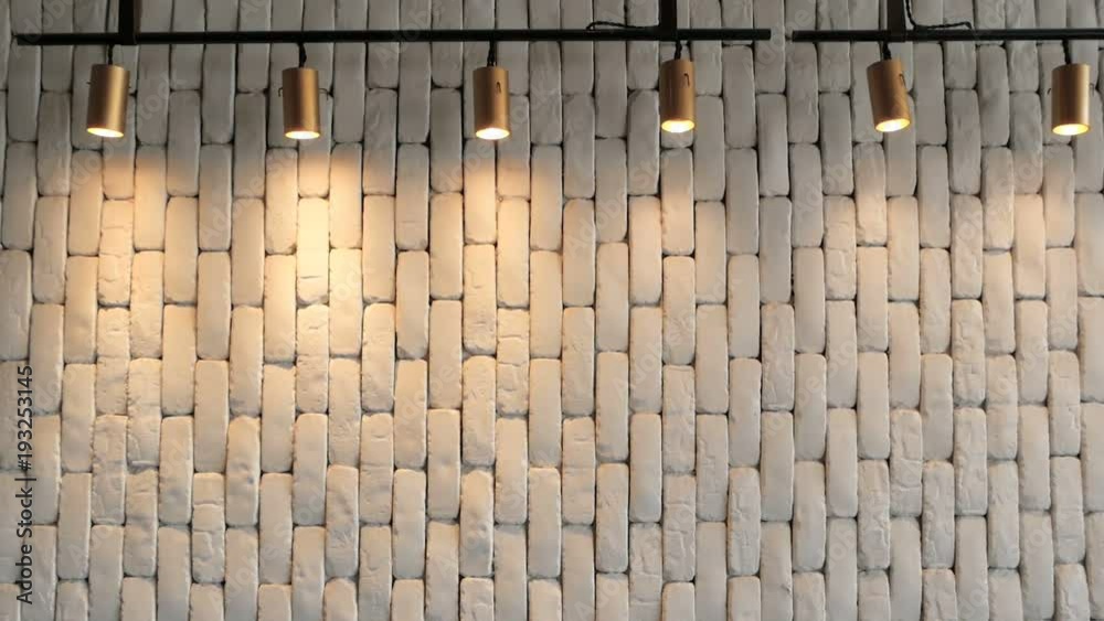 The white brick wall is hilighted with lanterns from above. Texture for background. Empty cement plane. Soft light from lamps is reflected from the wall. Retro loft space in a hipster style.