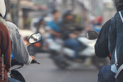 motocycles with riders wait for go light sign on cross junction road with passengers ,back view