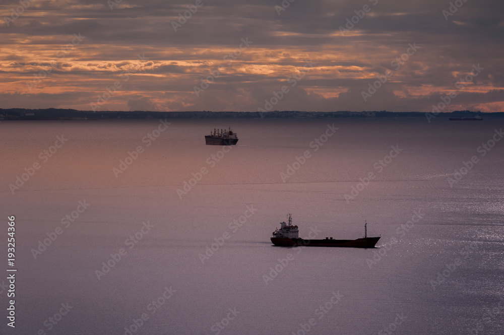 Seascape with ships and cloudy sky at sunset.