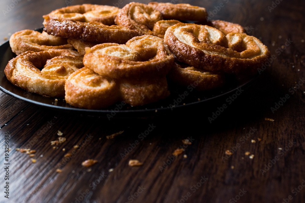 Palmier Cookies in Black Plate on Wooden Surface.