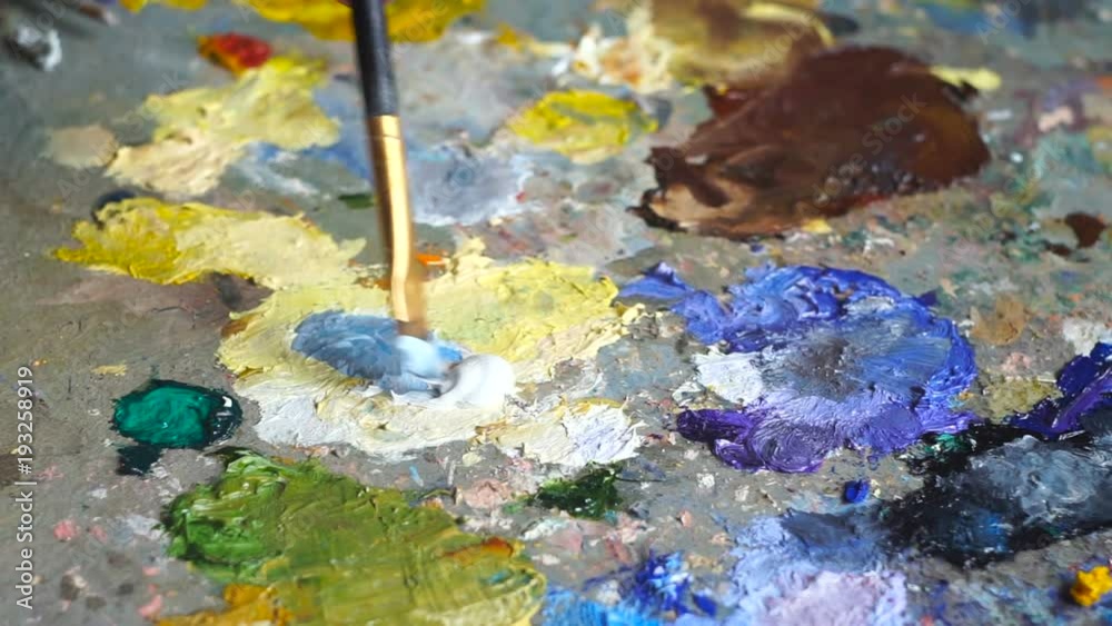 Artist brush mix color oil painting on palette. Painter at the studio. Artist brush mix color oil painting on palette. Painter at the studio.