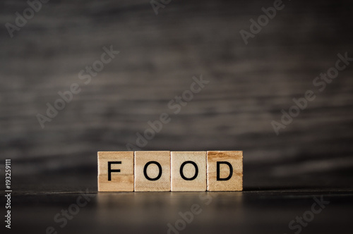 the word food consists of light wooden square panels on a dark wooden background