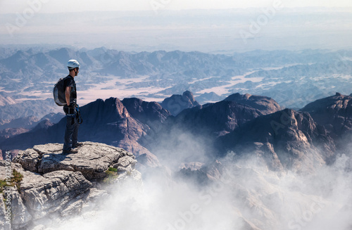 Mountain climber standing on summit with vast view