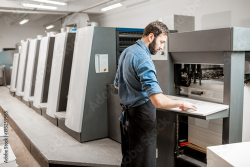 Printing operator working with offset machine at the printing manufacturing photo