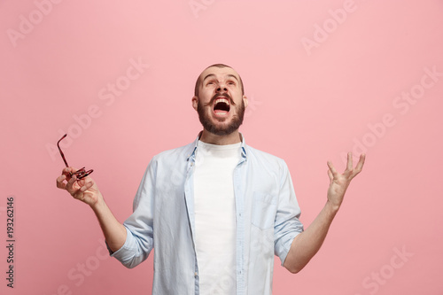 The young emotional angry man screaming on pink studio background photo