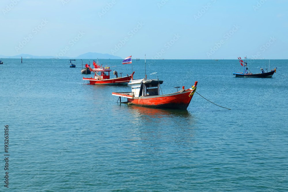 Fishing boats lie at anchor by the sea, with Blue sky and clouds background