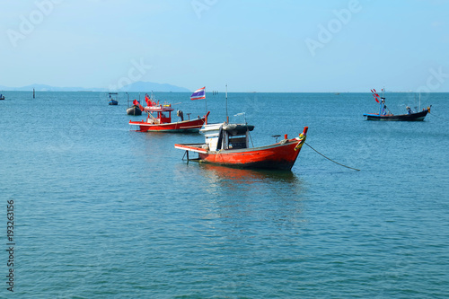 Fishing boats lie at anchor by the sea, with Blue sky and clouds background