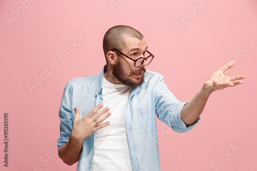 Beautiful male half-length portrait isolated on pink studio backgroud. The young emotional surprised man