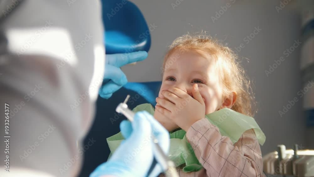 Little cute girl in the dentist's office does not want to be treated, resisting and closing her mouth with her hands Little cute girl in the dentist's office does not want to be treated, resisting and closing her mouth with her hands
