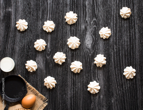 Sweet white meringue and other components on a wooden background, free space for text.